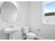 Modern powder room featuring a pedestal sink, white fixtures, and a window for natural light at 749 Aristocrat Ln, Knightdale, NC 27545