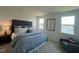 Calm main bedroom boasts tufted headboard, bedside table with lamp, and two large windows at 813 Emmer St, Rolesville, NC 27571