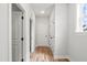 Hallway with white walls, wood-look flooring, and white doors with black hardware and trim at 9169 Dupree Meadow Dr # 26, Angier, NC 27501