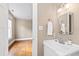 This bathroom features a white vanity, tan walls, chrome fixtures, and a doorway to a room with hardwood floors at 101 S Bloodworth St, Raleigh, NC 27601