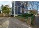 View of a blue house features stone walls, lush greenery, and a gravel driveway at 101 S Bloodworth St, Raleigh, NC 27601