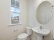 New half bathroom featuring a white pedestal sink, round mirror, and ample natural light at 107 Willow Cameron Way, Angier, NC 27501