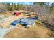 Aerial view of a house with a red barn, sheds, and carports on land surrounded by trees at 1211 Palmers Chapel Church Rd, Siler City, NC 27344