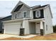 Two-story home with stone accents, gray siding, covered entrance, and a two-car garage at 135 Willow Cameron Way, Angier, NC 27501