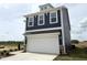 Newly built home with blue vinyl siding, a white two-car garage, and professional landscaping at 136 Willow Cameron Way, Angier, NC 27501
