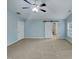 Large bedroom with neutral carpet, a ceiling fan, light blue walls, and a sliding barn door at 151 N Great White Way, Clayton, NC 27527