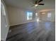 Spacious living area featuring gray wood floors, a ceiling fan, and ample natural light from large windows at 5520 Neuse View Dr, Raleigh, NC 27610