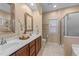 Bathroom featuring a double sink vanity, framed mirror, and a glass-enclosed shower with tile surround at 5618 Wade Park Blvd, Raleigh, NC 27607