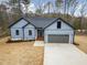 An inviting blue home showcasing a well-manicured lawn, modern design, and an attached garage at 605 Shawnee Dr, Louisburg, NC 27549