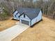 A blue home showcasing a well-manicured lawn, modern design, and an attached garage at 605 Shawnee Dr, Louisburg, NC 27549
