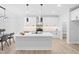 Modern kitchen with white cabinets, countertops and island with stainless steel appliances, and modern light fixtures at 605 Shawnee Dr, Louisburg, NC 27549
