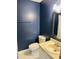 Bathroom with dark blue walls and a vanity featuring sink, toilet, and mirror at 6520 Thetford Ct, Raleigh, NC 27615