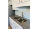 A close-up of a stainless-steel sink in a kitchen with grey countertops and white cabinets at 6520 Thetford Ct, Raleigh, NC 27615