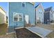 Rear view of the blue house featuring a small patio and minimal landscaping at 781 Fireball Ct, Knightdale, NC 27545
