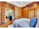 A bedroom with wood paneled walls, a queen bed, and an open door to a living area at 807 Vickers Ave, Durham, NC 27701