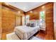 Cozy bedroom with wood paneled walls, hardwood floors, and windows with green views at 807 Vickers Ave, Durham, NC 27701