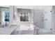 Elegant bathroom boasts a soaking tub, a glass shower, and a serene backyard view at 100 Cloud Berry Ln, Holly Springs, NC 27540
