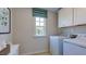 Bright laundry room featuring a window, white washer and dryer, cabinets and a stylish striped shade at 100 Cloud Berry Ln, Holly Springs, NC 27540