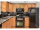 Well-lit kitchen with wood cabinets, granite countertops, and black appliances at 108 Ephesus Church Rd # 510, Chapel Hill, NC 27517