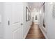 Hallway with wood floors, white trim, wall decor, and mirrors leading toward a door with glass insert at 1702 Red Roses Ave, Durham, NC 27703