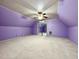 Spacious attic room with purple walls, neutral carpet, and a ceiling fan, creating a versatile living space at 1809 Waddill Way, Henderson, NC 27536