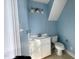 Light-filled bathroom with single sink vanity, three-light fixture, and toilet beneath the sloped ceiling at 1809 Waddill Way, Henderson, NC 27536