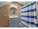 Bathroom with blue and white striped shower curtain, round mirror, and grey vanity at 35 Henry Rifle Ln, Angier, NC 27501