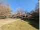 A yard space and driveway with houses in the background, lush greenery, and a clear blue sky at 3501 Turnbridge Dr, Raleigh, NC 27609