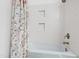 Clean white bathroom featuring tub with white floral curtain and tiled wall with built-in shelving at 3716 Yorktown Pl, Raleigh, NC 27609