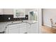 Bright kitchen featuring white cabinets, a granite countertop, black subway tile backsplash and stainless steel sink at 3716 Yorktown Pl, Raleigh, NC 27609