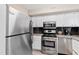 Well-equipped kitchen with stainless steel appliances, white cabinets, granite countertops, and sleek dark backsplash at 3716 Yorktown Pl, Raleigh, NC 27609