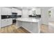 Modern kitchen featuring an island, stainless steel appliances, white cabinets, and a black backsplash at 376 Buckhorn Branch Park # 38, Clayton, NC 27520
