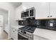 Stove and microwave area with white cabinets and a black backsplash in a modern kitchen design at 376 Buckhorn Branch Park # 38, Clayton, NC 27520
