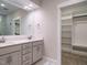 Bathroom featuring double sinks, white cabinets, a large mirror, and an organized walk-in closet at 428 Hampshire Ct, Four Oaks, NC 27524