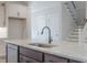 Kitchen island featuring granite countertops, stainless sink and faucet, with staircase in background at 428 Hampshire Ct, Four Oaks, NC 27524