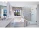Bright bathroom with a soaking tub and glass-enclosed shower features a large window overlooking a backyard at 615 Contento Ct, Sanford, NC 27330