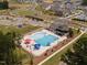Aerial view of a neighborhood pool with lap lanes, leisure areas, and playground near modern homes and green spaces at 617 Spellbrook Rd, Zebulon, NC 27597