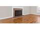 Cozy fireplace featuring a classic brick surround and hardwood floors in a naturally lit room at 6309 Charmco Ct, Wake Forest, NC 27587