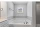 Soaking tub in bathroom with gray tile surround, accompanied by sleek fixtures and a window view at 741 Aristocrat Ln, Knightdale, NC 27545