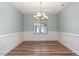 Dining room features wainscotting, a modern chandelier and hardwood floors at 89 Bison Ln, Lillington, NC 27546