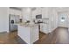 Modern kitchen featuring white cabinetry, stainless steel appliances, granite countertops, and hardwood flooring at 907 Field Ivy Dr, Fuquay Varina, NC 27526
