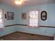 Bedroom with windows, lace curtains, neutral flooring and bright blue walls at 105 Lake Rd, Henderson, NC 27537