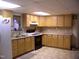 Bright kitchen featuring maple cabinets, white fridge, black range, and tile floor at 105 Lake Rd, Henderson, NC 27537