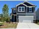Charming two-story home showcasing a clean white garage door and complemented by tastefully dark blue siding at 106 Little Creek Dr, Lillington, NC 27546