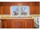 Close-up of a traditional kitchen with wooden cabinets, a sink beneath a window, and neutral walls at 1231 Carolina St, Graham, NC 27253