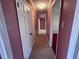 Hallway featuring three doors, neutral carpet, and mauve painted walls at 1926 W Front St, Burlington, NC 27215