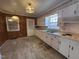 Spacious kitchen featuring white cabinetry, vintage wallpaper, wood paneling, and ample natural light at 1926 W Front St, Burlington, NC 27215