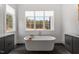 A modern bathroom featuring a soaking tub, double windows, and stone countertops at 299 Seaforth Landing Dr, Pittsboro, NC 27312