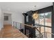 Upstairs hallway with decorative light fixture, wood floors, and iron railing at 299 Seaforth Landing Dr, Pittsboro, NC 27312