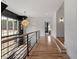 Bright hallway features wood floors, modern light fixtures, and railing overlooking the stairs at 299 Seaforth Landing Dr, Pittsboro, NC 27312